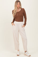 woman wearing a brown ribbed long sleeve henley top and beige wide-leg pants with pockets, paired with white sneakers