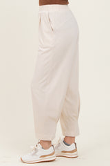 woman wearing light beige relaxed fit trousers with side pockets and cuffed hems, paired with white sneakers