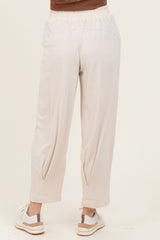 woman wearing light beige loose-fitting pants with an elastic waistband and tapered legs, seen from the back