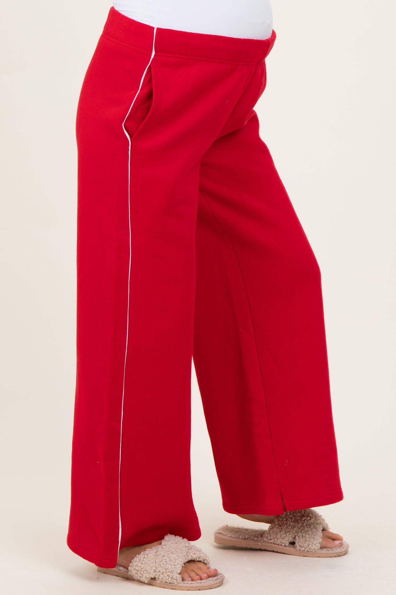 maternity wear red wide-leg pants with white piping details, model wearing them and showing a baby bump