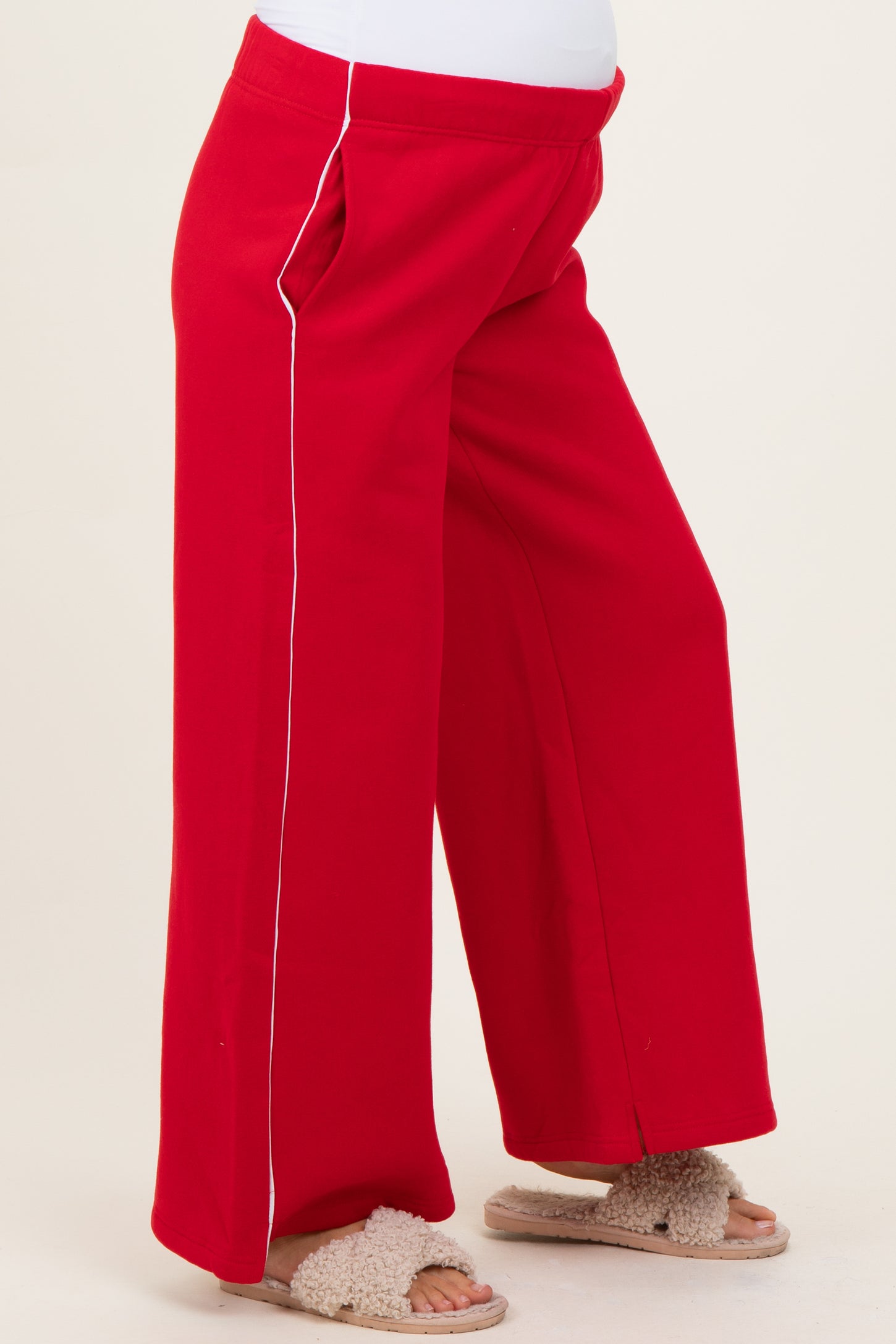 maternity wear red wide-leg pants with white piping details, model wearing them and showing a baby bump