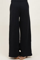 woman wearing black wide leg lounge pants with an elastic waistband, shown from the back