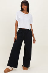 woman wearing a white short sleeve top and black wide-leg pants with a drawstring waist and side slits