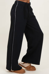 woman wearing black wide-leg sweatpants with white side stripe and tan slippers