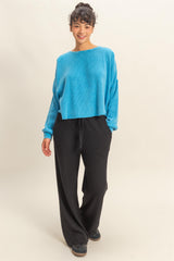 woman wearing a cropped blue ribbed sweater and black wide-leg pants