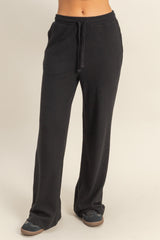 woman wearing black wide-leg lounge pants with a drawstring waist and two side pockets