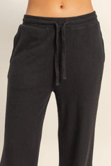 woman wearing black ribbed lounge pants with an elastic waistband and drawstring detail