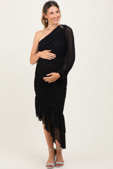 woman wearing a black one-shoulder maternity dress with ruched details and a ruffled hem, holding her baby bump