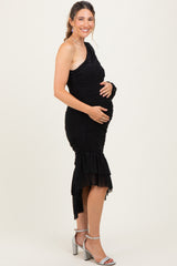 woman wearing a black one-shoulder maternity dress with ruching and ruffled hem, holding her baby bump