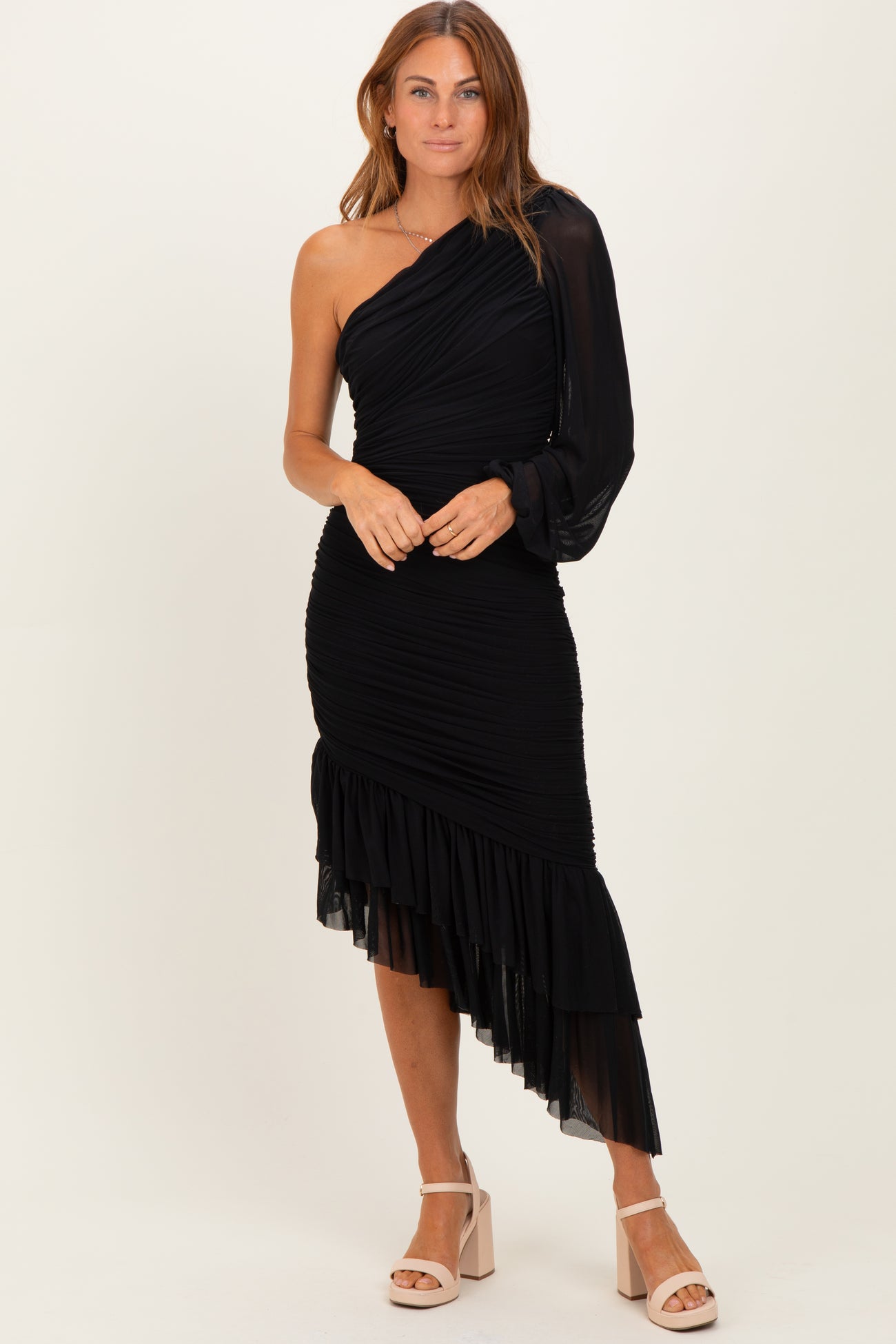 woman wearing a black one-shoulder dress with ruched details and an asymmetrical hemline
