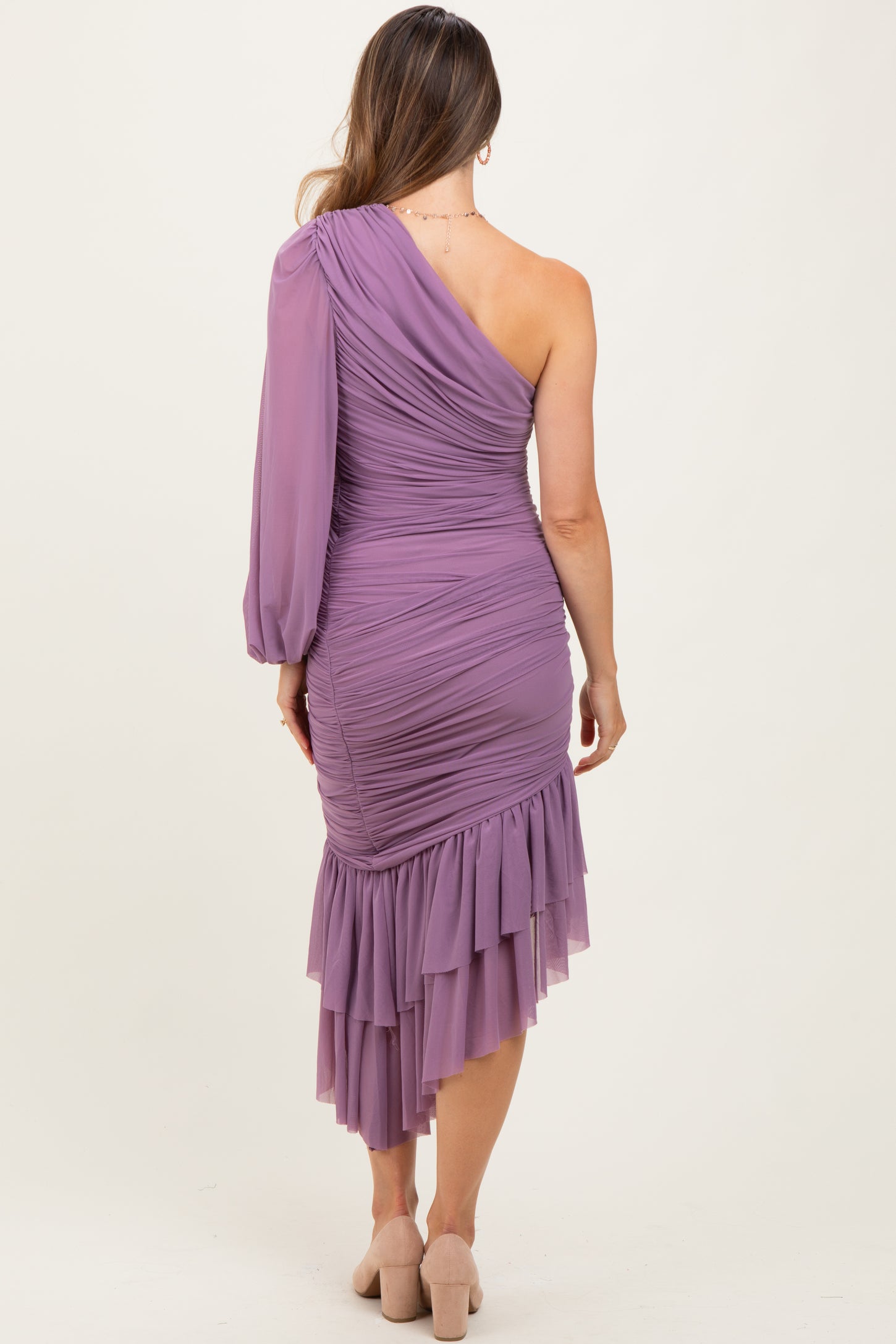 woman wearing a lavender one-shoulder maternity dress with ruched detail and a ruffled hemline