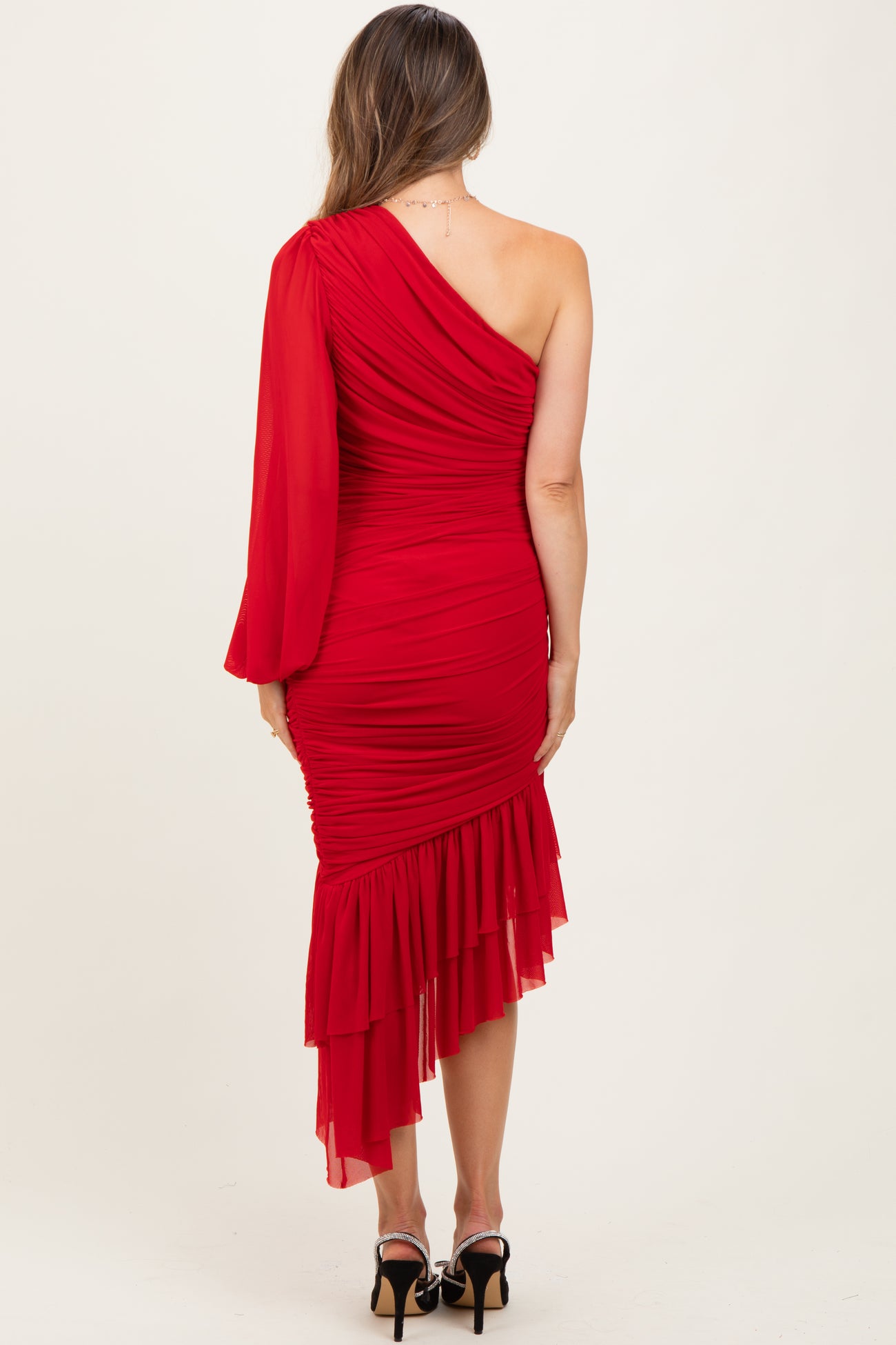 woman wearing a red one-shoulder maternity dress with ruffle details and a fitted silhouette
