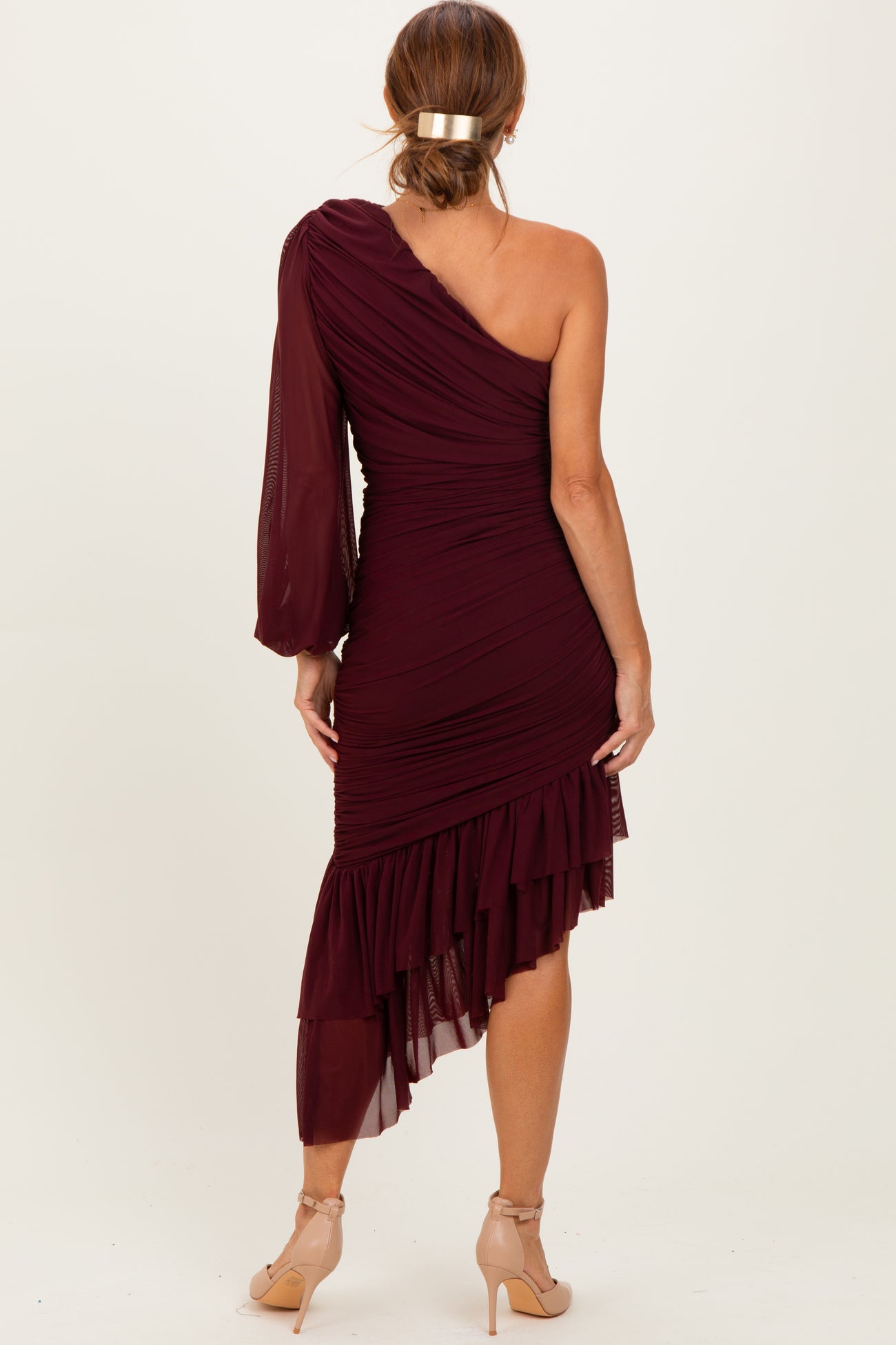woman wearing a burgundy one-shoulder dress with ruched detailing and a layered ruffled hem