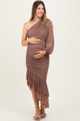 woman wearing a brown one-shoulder maternity dress with ruched detailing and ruffle hem, holding her baby bump