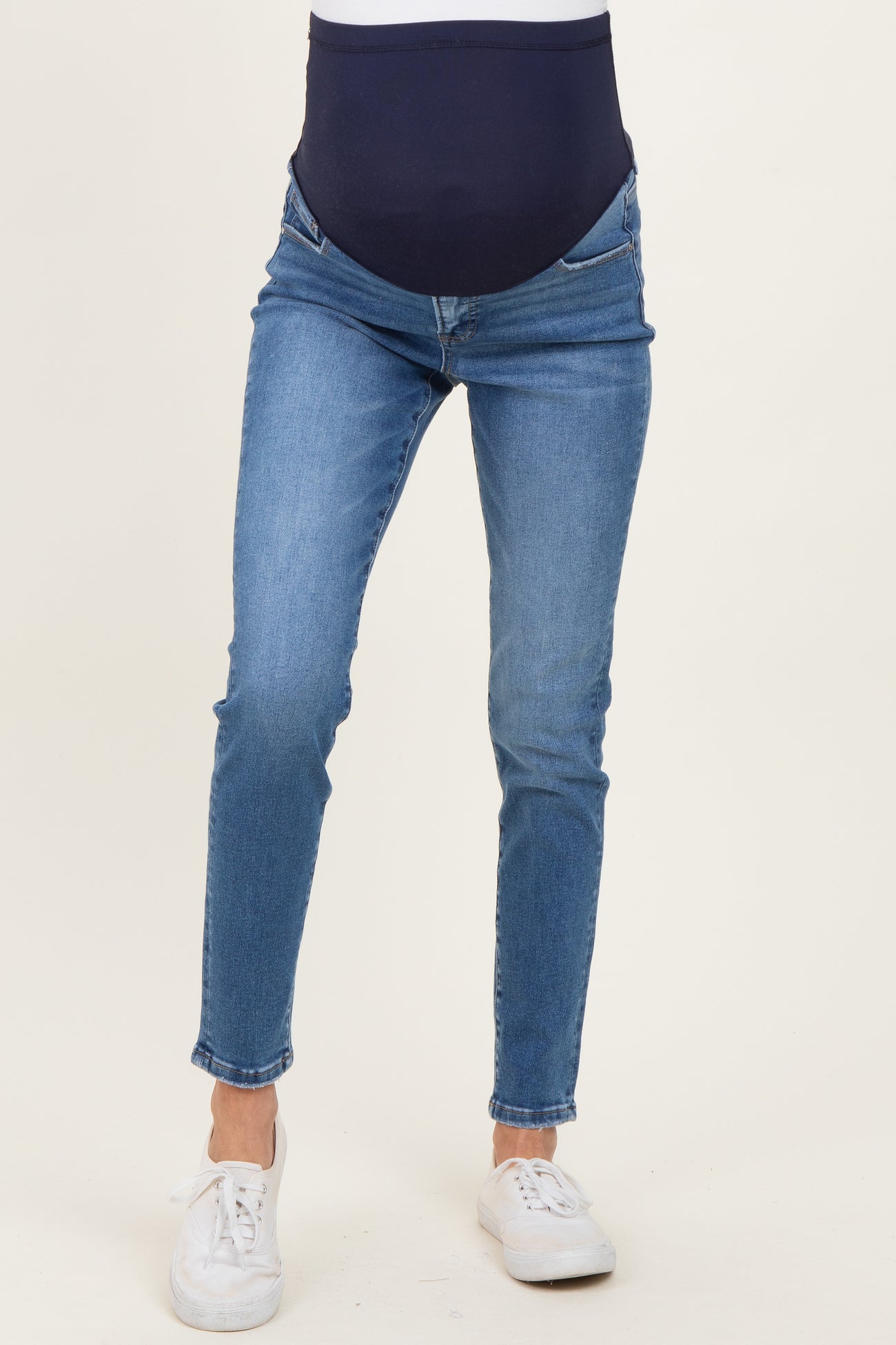 woman wearing dark blue maternity jeans with a supportive belly band, styled slim fit and cropped length
