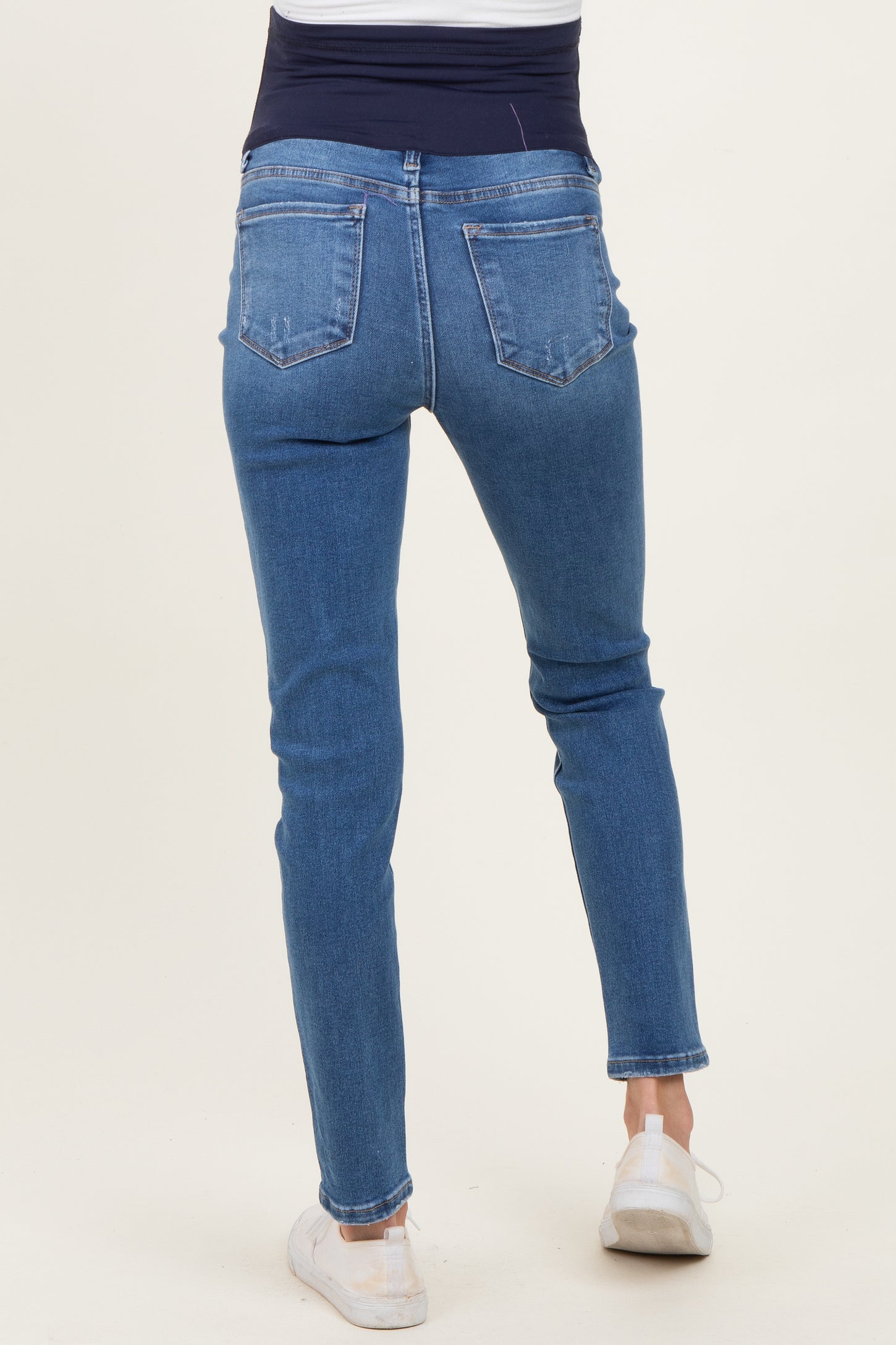 woman wearing blue maternity skinny jeans, showing the back view with a stretchy waistband