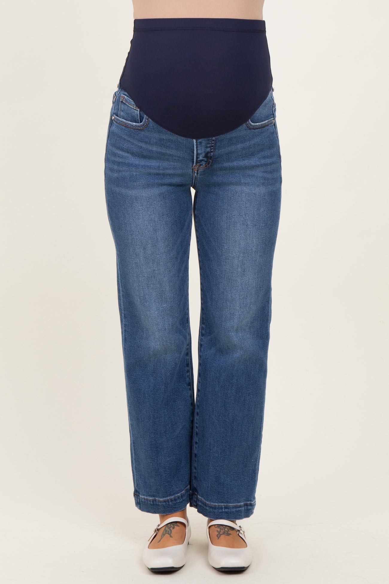 woman wearing a pair of maternity jeans with a dark blue over-the-bump waistband and light blue straight-leg denim.