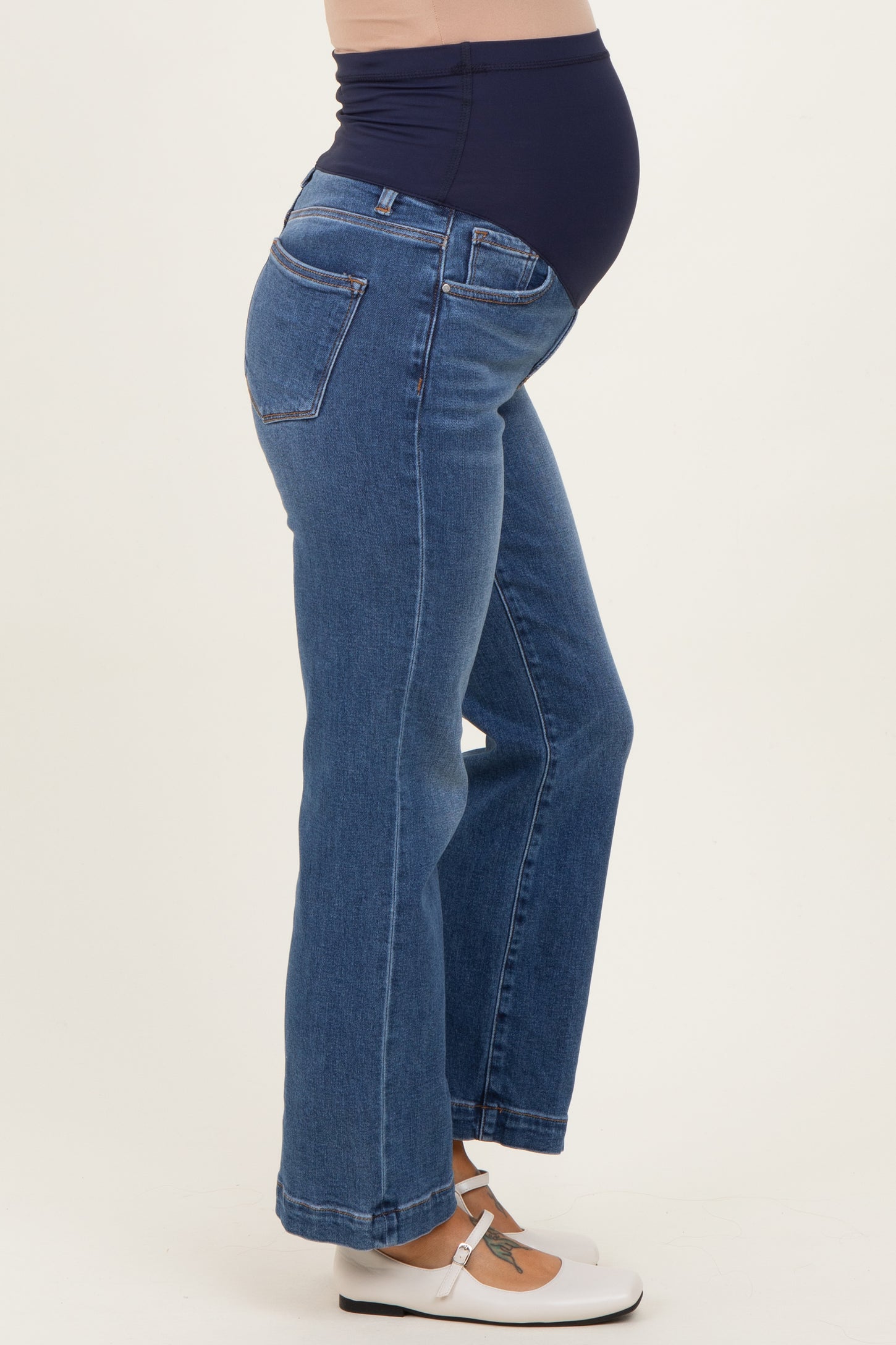 woman wearing blue maternity jeans with a supportive belly panel and a visible baby bump
