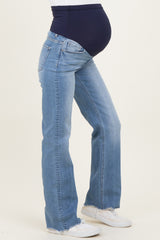 woman wearing light blue maternity flared jeans with a dark blue over-the-bump band and visible baby bump