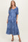 woman wearing a blue floral maternity maxi dress with puff sleeves and a defined waist, showcasing her baby bump