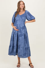 woman wearing a blue floral maternity dress with puff sleeves and a visible baby bump