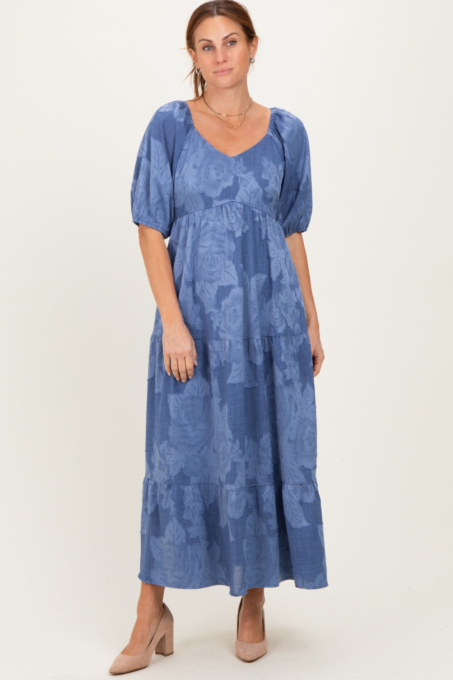 woman wearing a blue floral maxi dress with puff sleeves and a tiered skirt, styled with nude heels