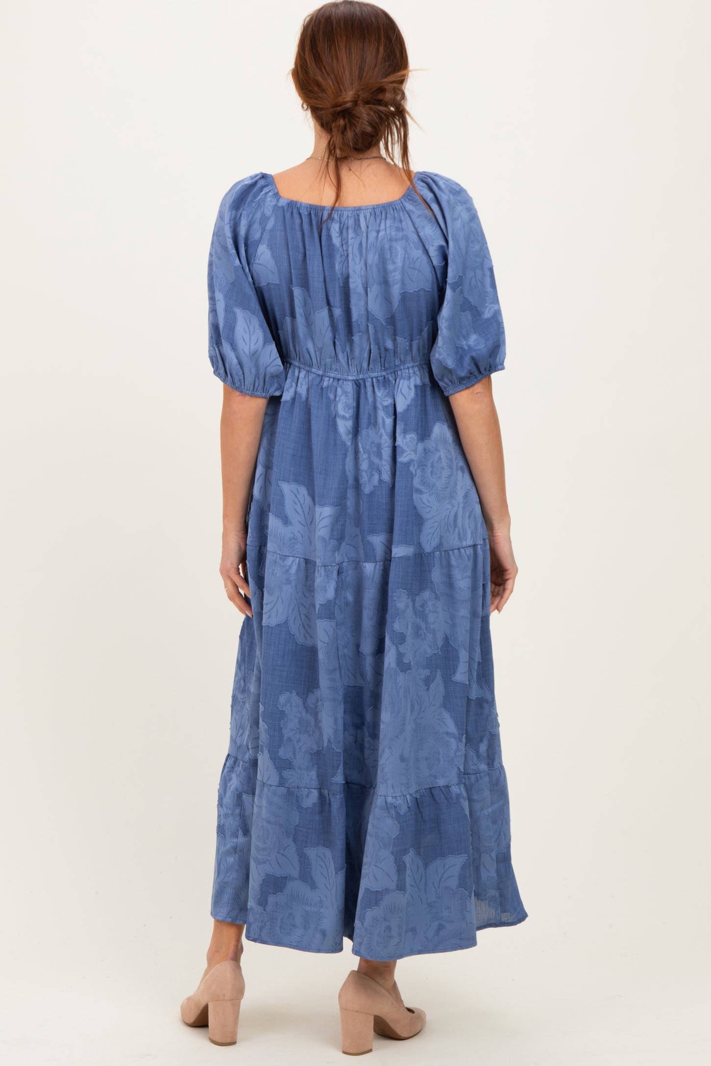 woman wearing a blue floral maxi dress with puff sleeves and a tiered skirt, shown from the back