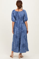 woman wearing a blue floral maxi dress with puff sleeves and a tiered skirt, shown from the back