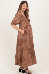 woman wearing a brown floral print maternity maxi dress with pockets and a visible baby bump