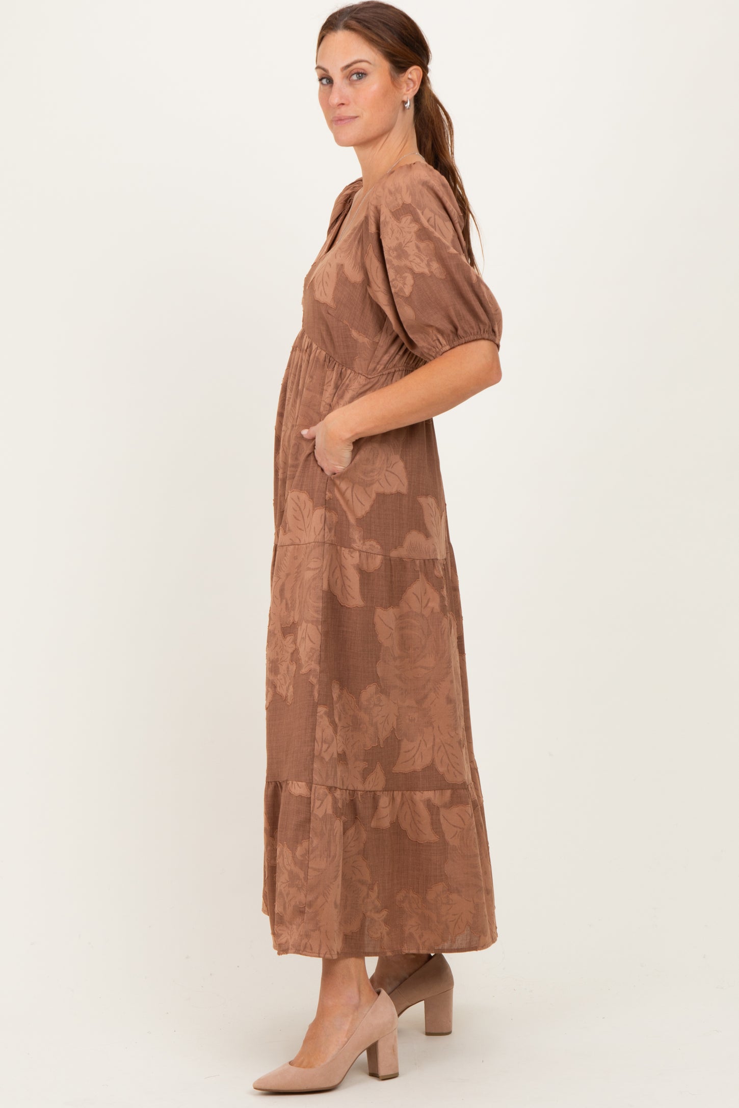 woman wearing a brown floral maxi dress with puff sleeves and pockets, standing sideways