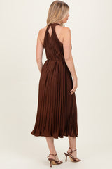 woman wearing a brown pleated midi dress with a halter neck and open back, styled with strappy heels