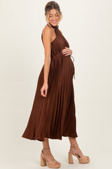 woman wearing a brown pleated maternity dress featuring a tie waist and showing her baby bump