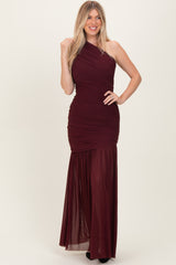 woman wearing a burgundy one-shoulder gown with ruching and a flowy skirt.