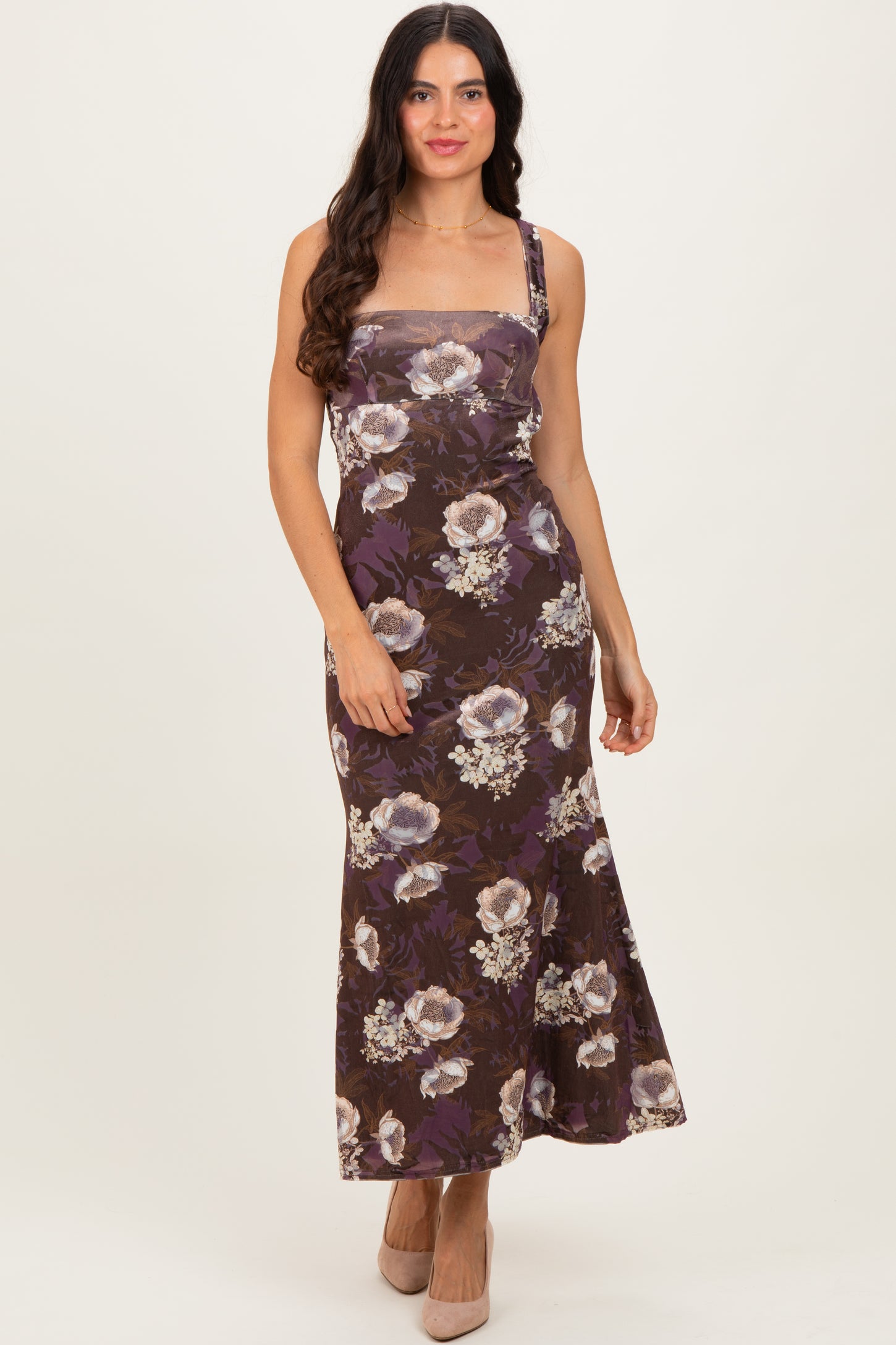 woman wearing a floral print brown maxi dress with spaghetti straps and a fitted silhouette