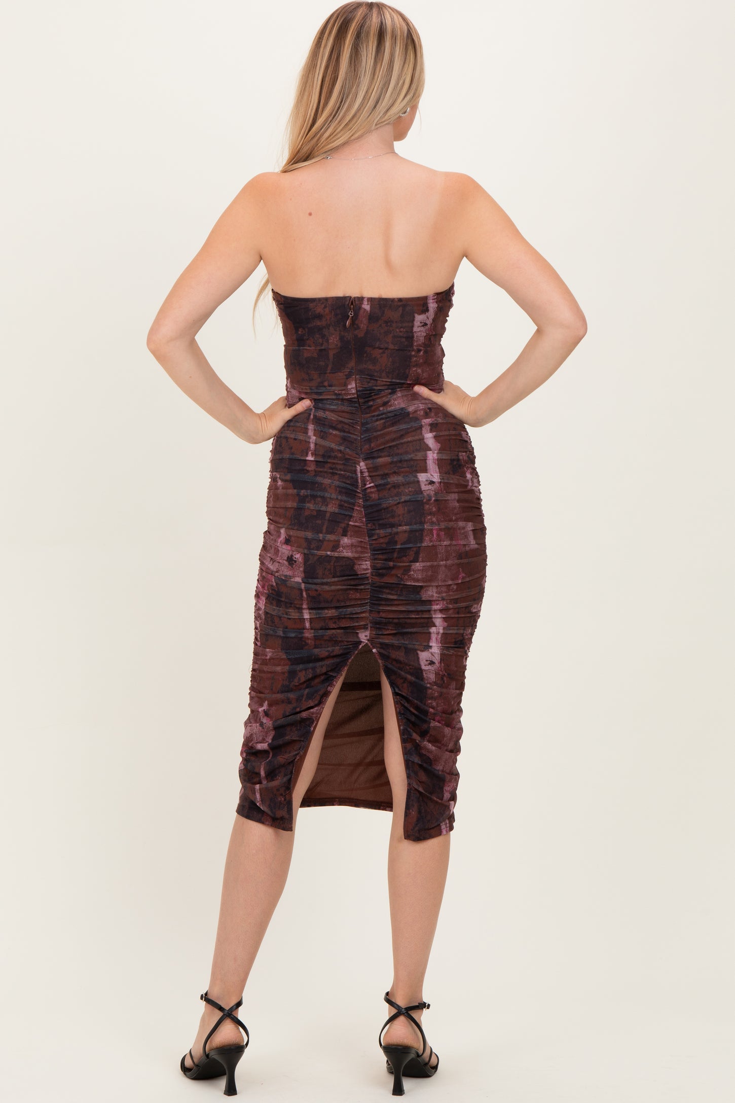 woman wearing a brown tie-dye midi dress with ruching and side slit, viewed from the back