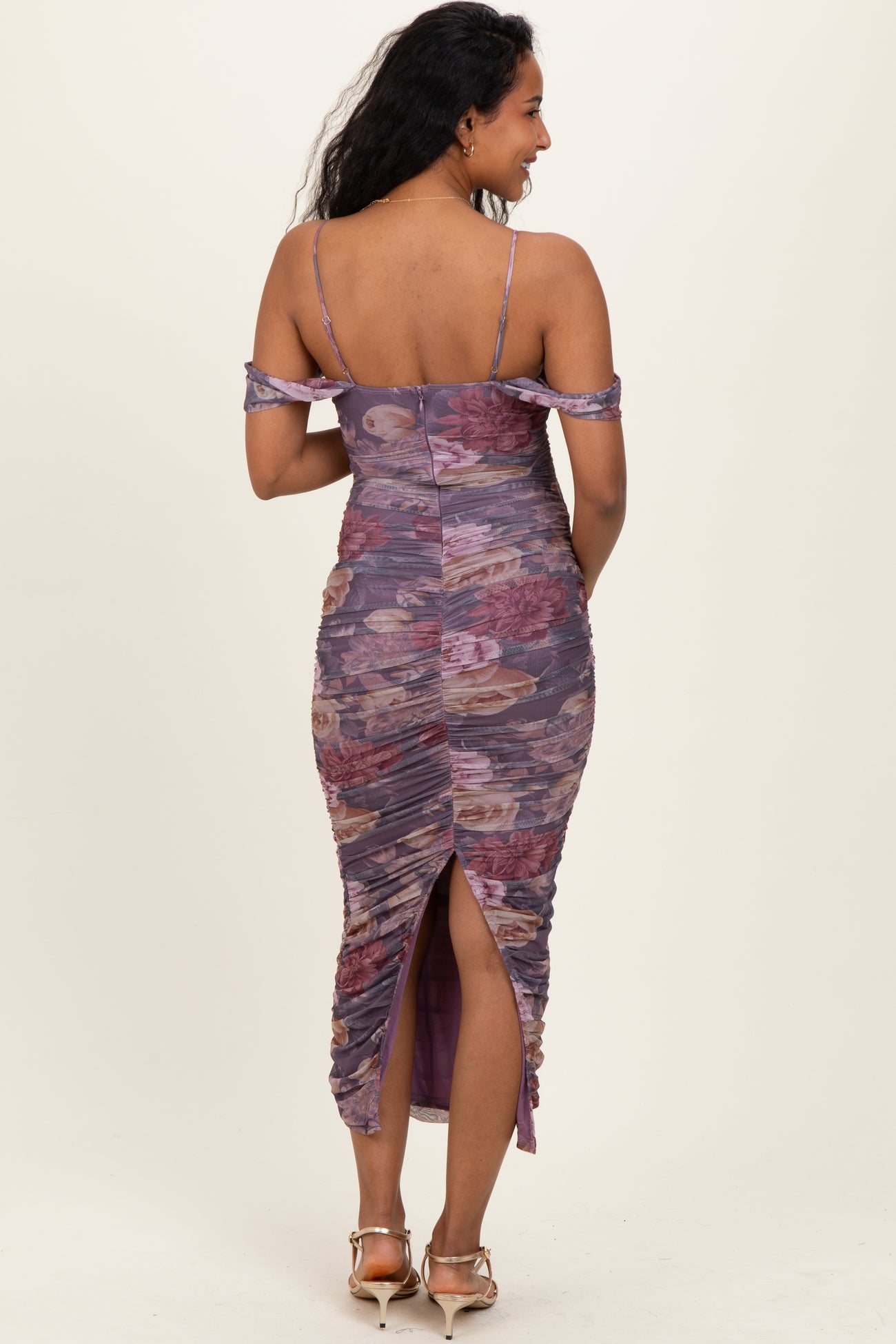 woman wearing a purple floral off-shoulder maternity dress with ruching and a side slit