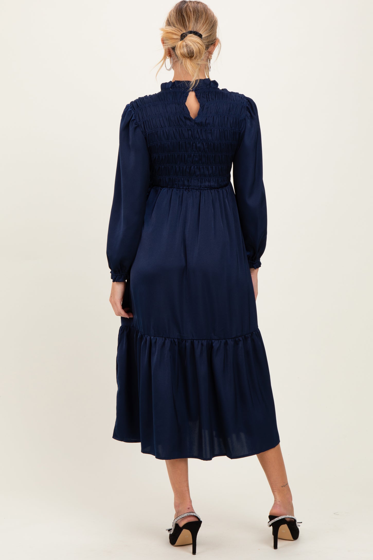 woman wearing a navy blue long sleeve maternity dress with smocking and a tiered skirt, viewed from the back