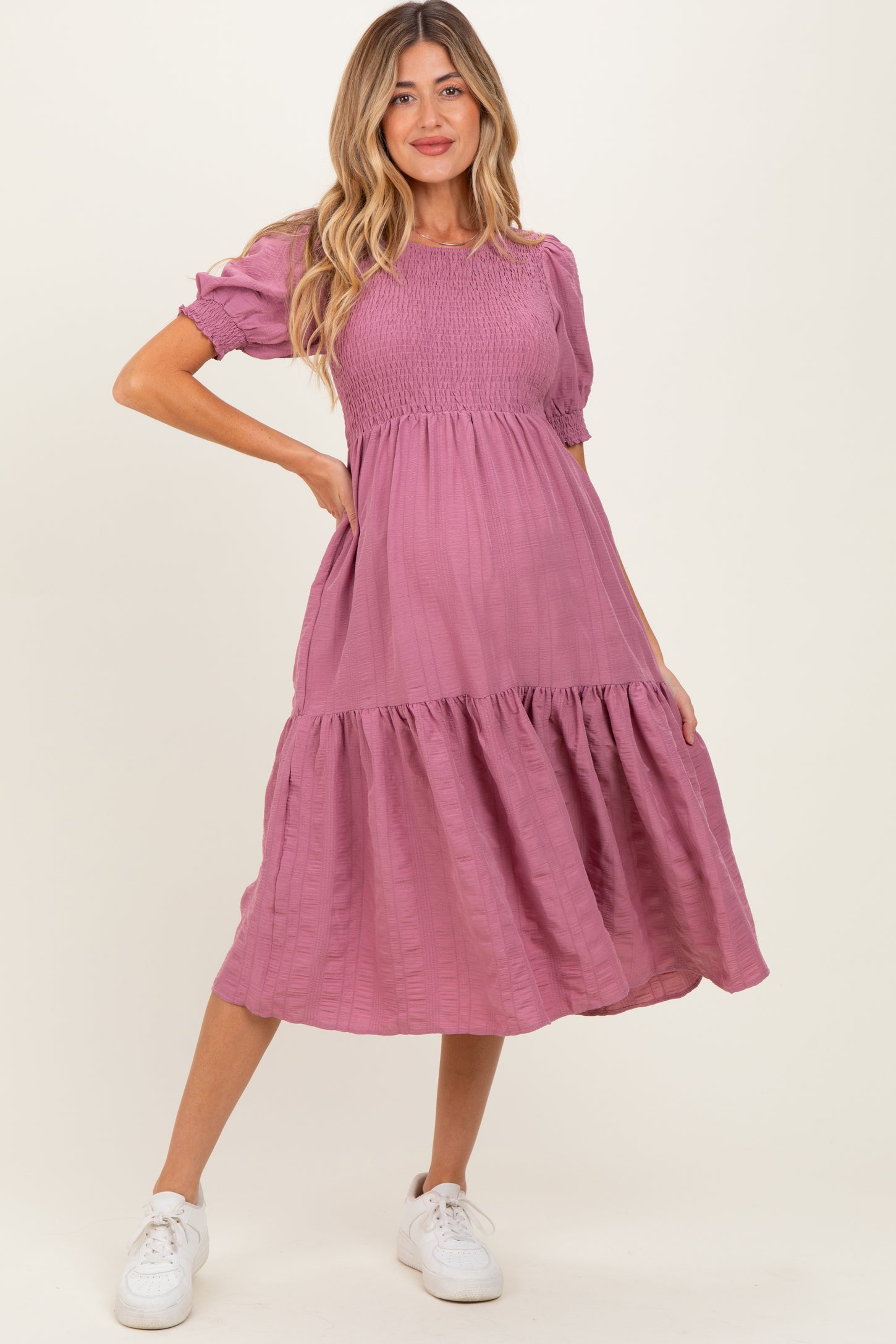 woman wearing a dusty rose maternity dress with short puff sleeves and a tiered skirt, showing her baby bump