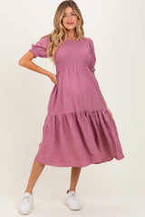 woman wearing a dusty rose maternity dress with short puff sleeves and a tiered skirt, showing her baby bump
