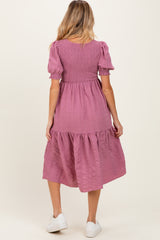 woman wearing a pink maternity dress with puff sleeves and tiered skirt, showing her back