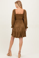 woman wearing a brown maternity dress with a smocked bodice and ruffled hem, showing her back