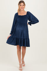 woman wearing a navy blue maternity dress with smocked bodice and flared skirt, showing off her baby bump