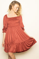 woman wearing a rust-colored smocked sundress with puff sleeves and a tiered skirt