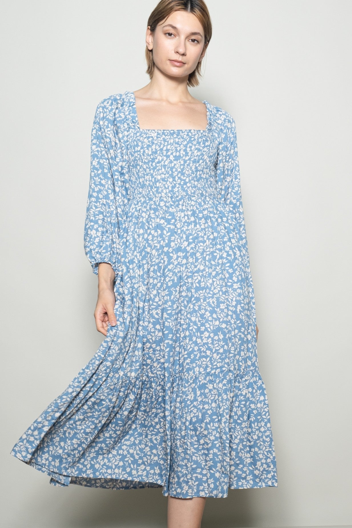 woman wearing a light blue floral long sleeve maxi dress with a square neckline and flowy skirt
