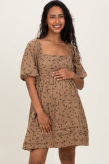 woman wearing a brown floral print maternity dress with puff sleeves and a square neckline, holding her baby bump