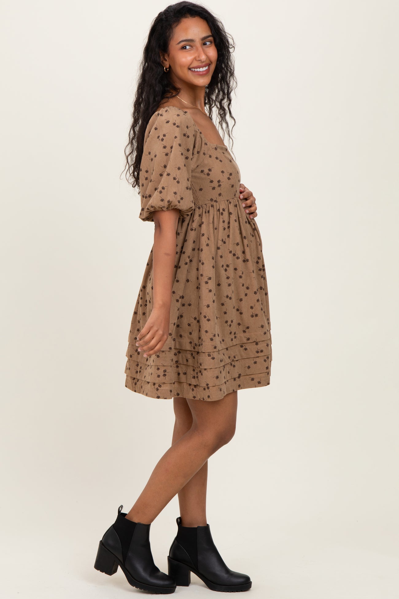 woman wearing a brown maternity dress with floral print and puff sleeves, showing her baby bump