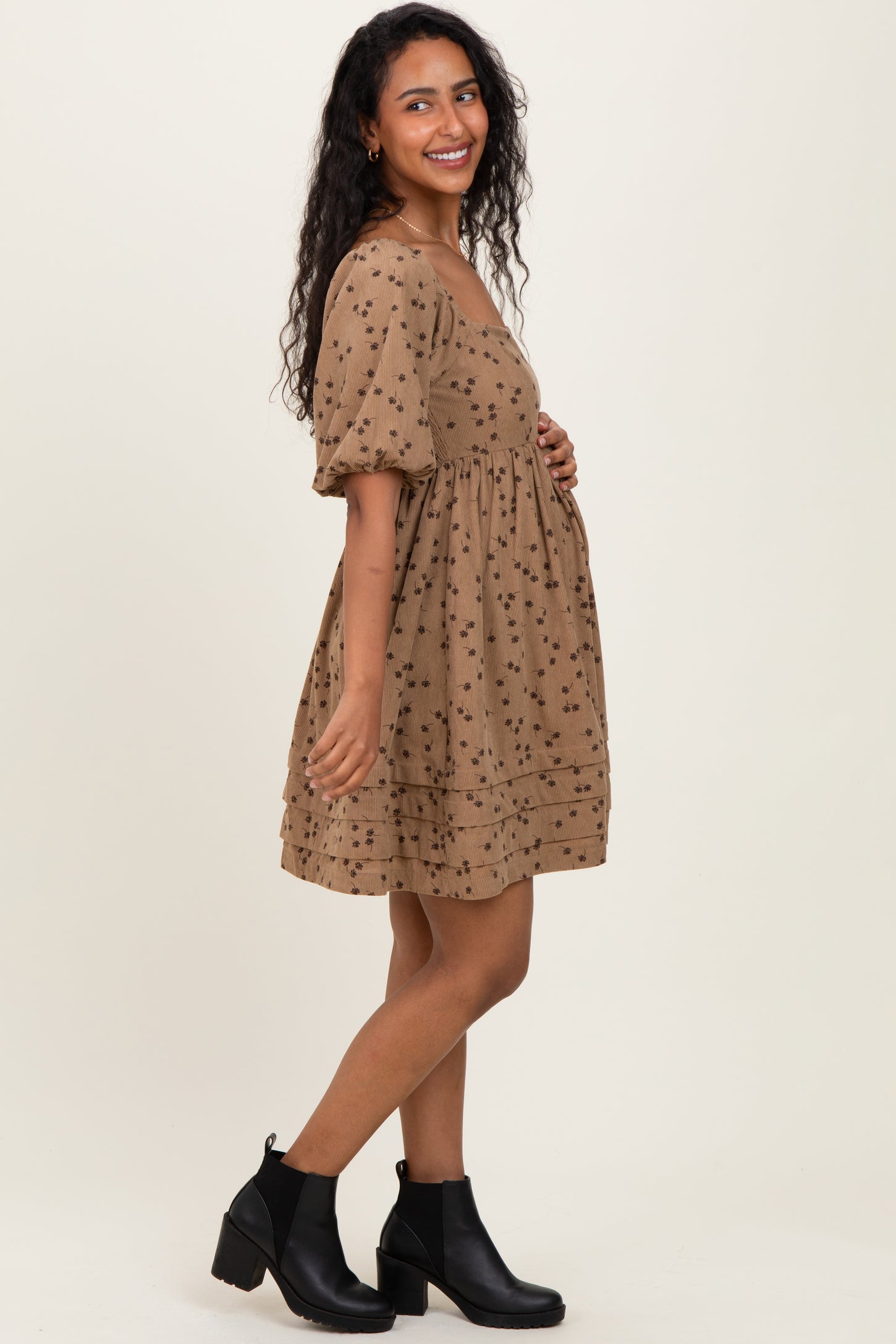 woman wearing a brown maternity dress with floral print and puff sleeves, showing her baby bump