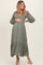 woman wearing a sage green maternity dress with puff sleeves and tiered ruffle hem, holding her baby bump