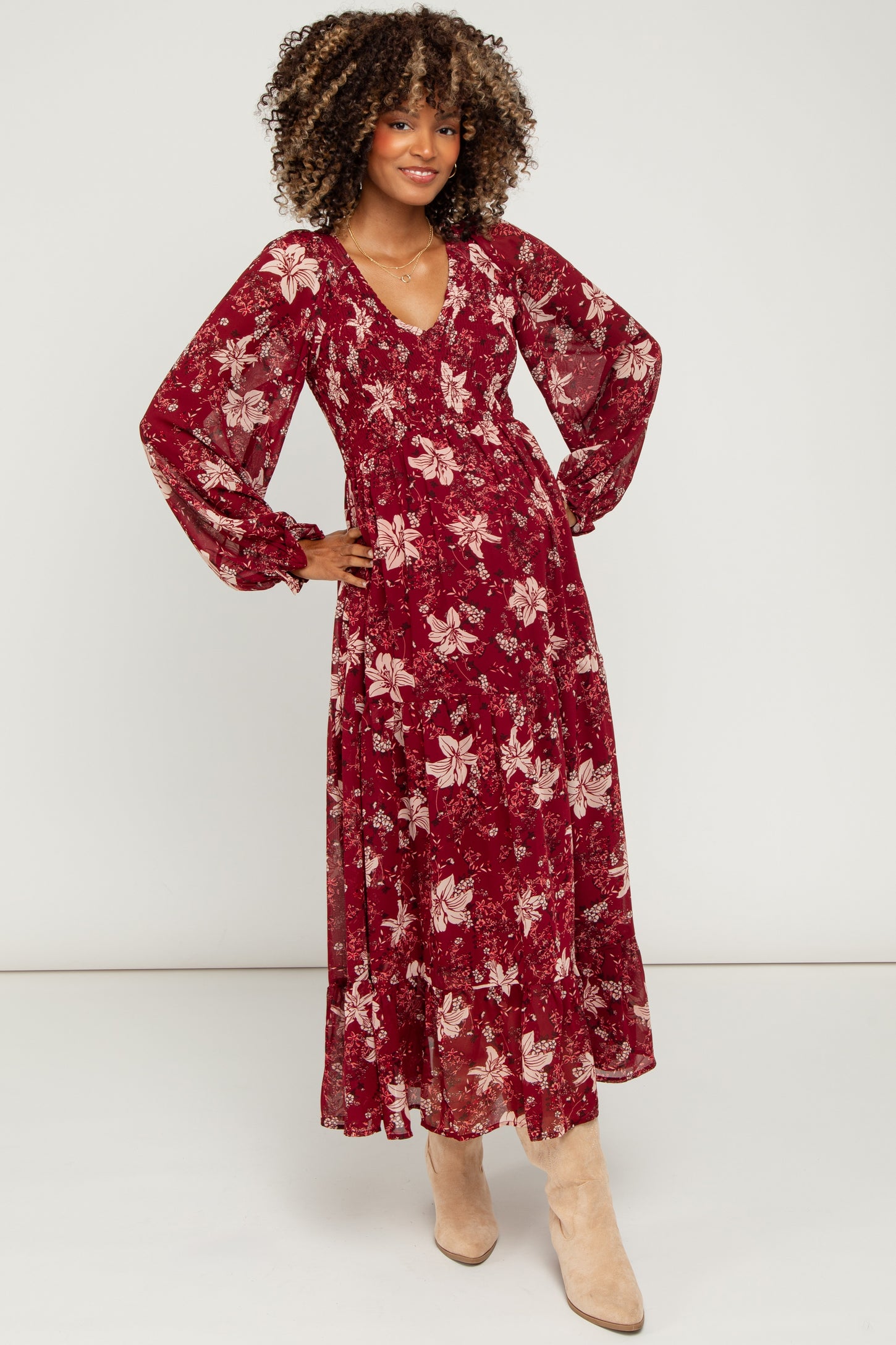 woman wearing a floral burgundy maternity maxi dress with long sleeves and a v-neckline, showing her baby bump