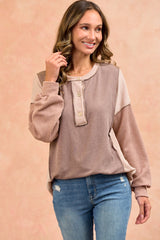 woman wearing a colorblock oversized sweater with button details and long sleeves, paired with blue jeans